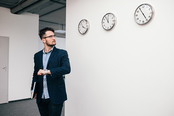 temps de travail effectifs : salarié regardant sa montre et des horloges sur le mur